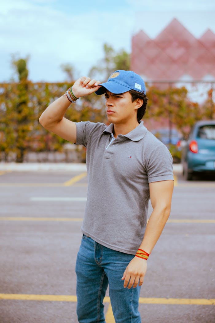Young man in casual outfit and cap standing outdoors, conveying confidence.